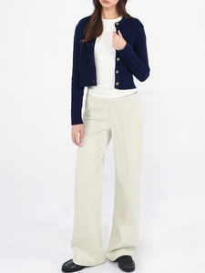 Detailed view of dark blue cable knit cardigan with white t-shirt and wide-leg trousers