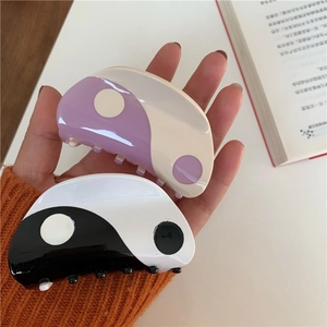 Detailed close-up of Yin Yang hair claws in purple and black with glossy finish