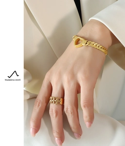 Detail of gold-plated stainless steel hollow heart bracelet and ring on a model