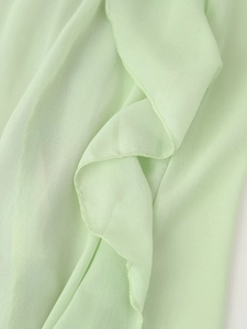 Nahaufnahme von hellgrünem Chiffonstoff mit Rüschenkanten und feinen Nähten