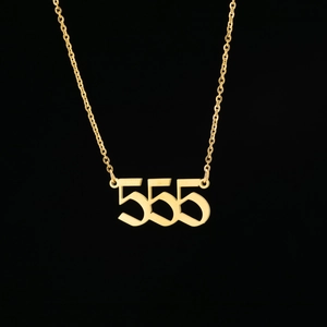 Détail macro du pendentif chiffre d'ange 555 doré avec police vintage sur une chaîne fine