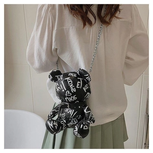 Close-up of black teddy bear crossbody bag with white graffiti and silver chain strap