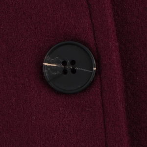 Close-up of the dark red wool blend fabric and textured button detail on the winter coat