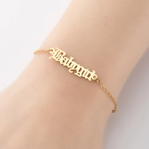 Makroaufnahme eines goldenen Babygirl Armbands mit gotischer Schrift am Handgelenk