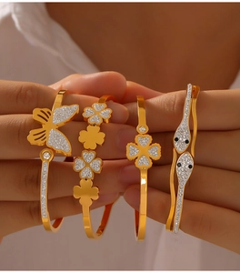 Detailed view of four gold-plated titanium steel bracelets with clover and butterfly charms