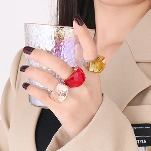 Three multi-faceted crystal glass rings in red, yellow, and pink on a 18K gold band