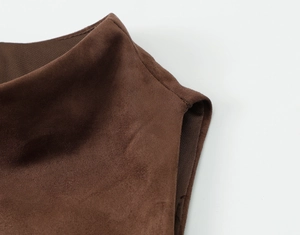 Gros plan sur les coutures fines et la texture suédine d'un haut marron foncé