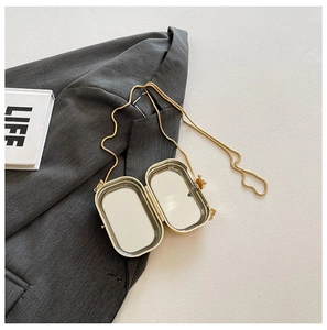 Close-up of golden acrylic lipstick bag featuring a built-in mirror and chain strap