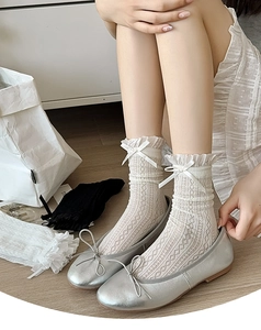 Close-up of white lace socks with bow detail and delicate hollow patterns for women