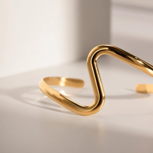 Detailed view of high-polished gold wave bangle with a minimalist curved design