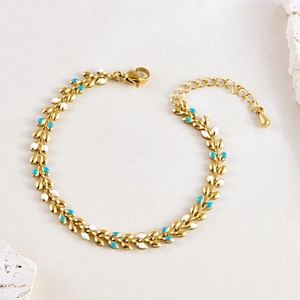 Detail of bohemian gold bracelet with blue and white enamel wheat leaves and lobster clasp