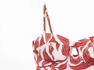 Detail of red leaf print on linen midi dress with adjustable straps and cutout design