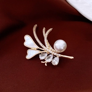 Detail view of 18k gold plated pearl and shell flower brooch on red silk fabric