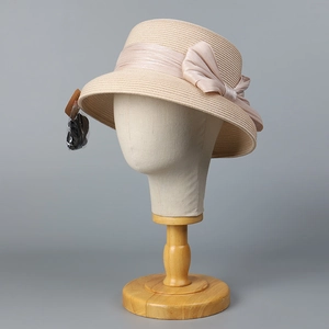 Dettaglio cappello da sole in paglia beige con nastro di seta rosa e fiocco elegante