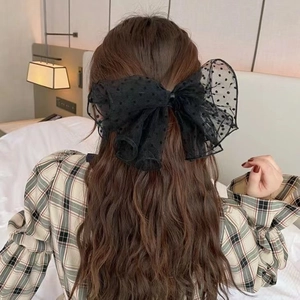 French style oversized black polka dot mesh bow hair clip worn by a model in a bedroom