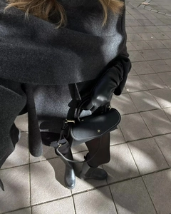 Close-up of black litchi leather handbag with gold star hardware worn with a wool coat