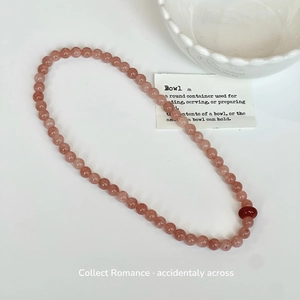 Detail of pink strawberry crystal beads with a dark red accent stone on white background