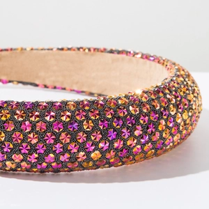 Detail of padded headband featuring gradient purple and gold rhinestones on white background
