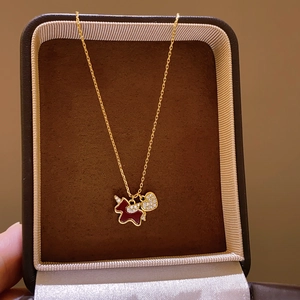 Close-up of gold-plated necklace with red horse and sparkling heart pendant on velvet box