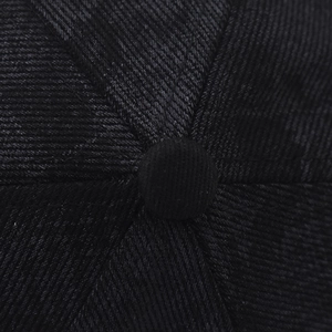 Detailed macro view of the black twill fabric crown and top button of the baseball cap