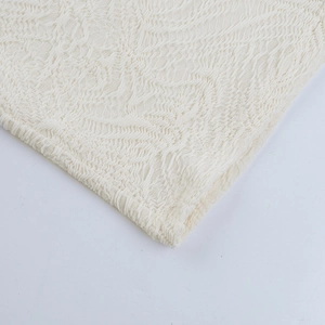 Close-up of the delicate white lace fabric and intricate wavy knit pattern detailing