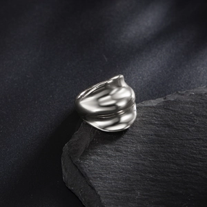 Vintage irregular silver wave ring for men with polished metallic finish on dark rock