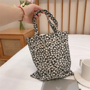 Detail of floral canvas tote bag held by hand in a warm bedroom setting