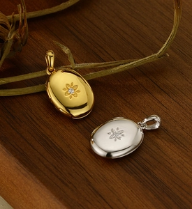 Macro detail of oval locket pendants with starburst design in gold and silver finish