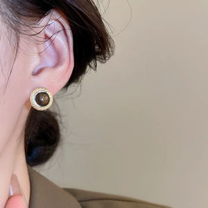 Detailed close-up of retro geometric tiger eye earring on model with golden spiral frame