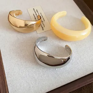 Ensemble de bracelets joncs épais minimalistes en or et argent sur plateau en bois