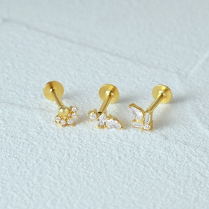 Detailed macro view of three gold 925 silver stud earrings with sparkling clear gemstones