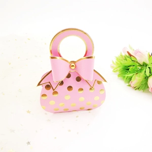 Detail of pink wedding favor box with gold foil dots and elegant ribbon bow accent