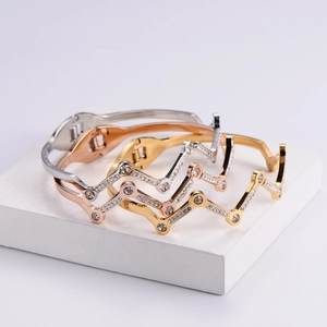 Three wave-shaped rhinestone bracelets in silver, gold, and rose gold on a white pedestal