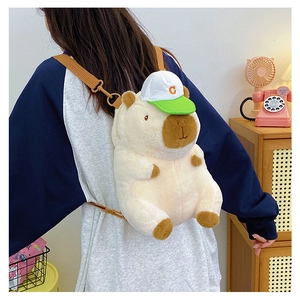 Detail of cute beige plush Capybara backpack with green cap on a model in a cozy setting