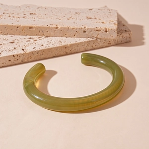 Detail of olive green translucent acrylic open cuff bracelet on stone background