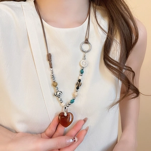 Detail of bohemian beaded necklace with amber heart pendant and turquoise stones