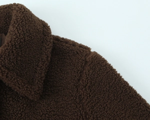 Detailed macro view of the lapel and shoulder seams on a brown teddy fleece coat