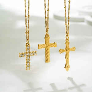 Detailed close-up of three gold-plated cross pendants featuring rhinestones and reliefs