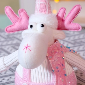 Close-up of pink and white Christmas reindeer doll with sequins and knitted textures