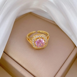 Adjustable gold ring featuring a sparkling pink round center stone and halo diamonds