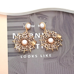 Creative spider web earrings with faux pearls on a fashion magazine background