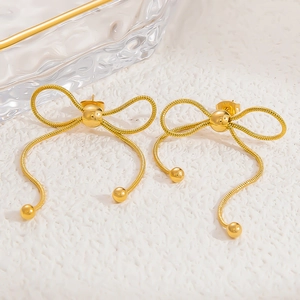 Detailed view of 18k gold plated bow stud earrings with snake chain and metal beads