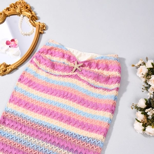 Détail d'une jupe en dentelle rayée avec motif au crochet coloré et charm étoile de mer dorée