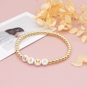 Macro shot of MAMA letter beads on a beaded bracelet with golden accents and dry flowers