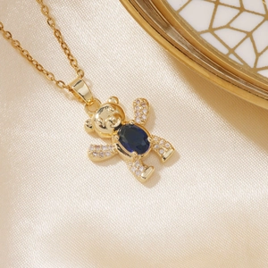 Detailed macro shot of golden bear pendant necklace with blue gem on beige silk