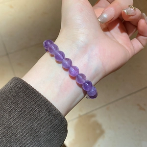 Detailed view of natural purple amethyst beaded bracelet worn on wrist with gold charm