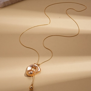 Macro shot of gold geometric pendant with elegant snake chain on a textured backdrop