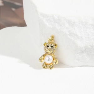 Macro shot of a gold bear pendant with micro-paved crystals and a large white pearl center