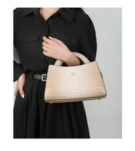 Beige crocodile embossed handbag with gold hardware and protective metal feet detail