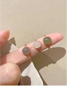 Three square stone rings in grey white and green on fingers with rose gold bands